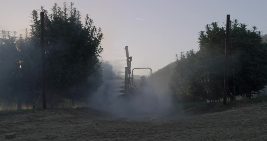 A farmer is spraying his crops at sunrise