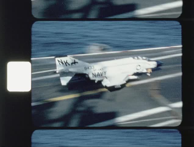 A fighter jet lands on an aircraft carrier