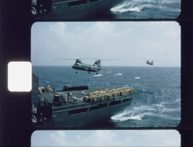 A helicopter lifts off the deck of a carrier at sea