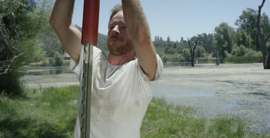 A man shoves a tool into the ground