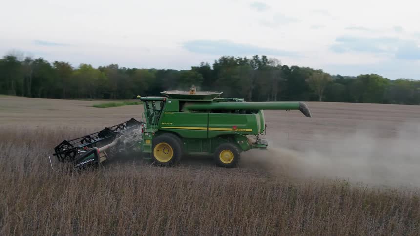 A farm tractor works the long field