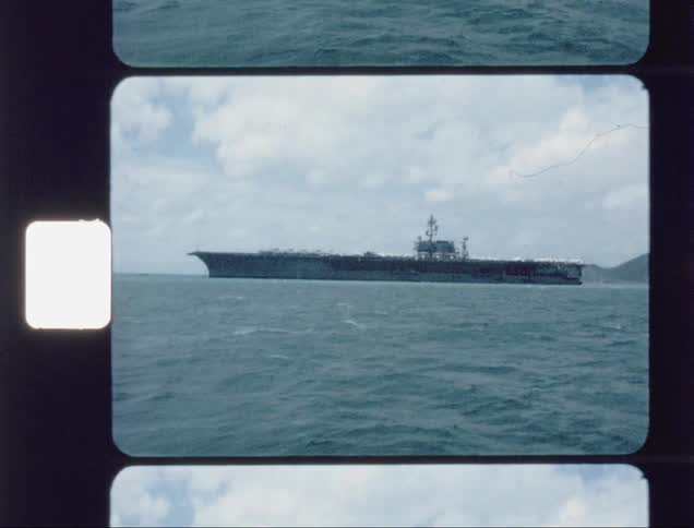 A large hangar ship sails in the water ahead