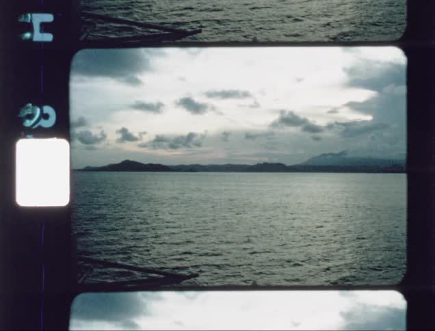 Sailors on a ship look out at the ocean at dusk