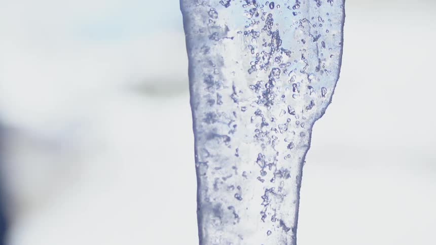 An icicle hangs outside on a cloudy day