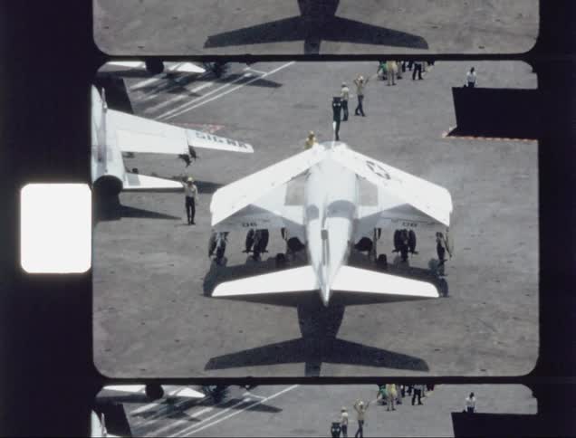 A jet is turning on the runway as people walk around