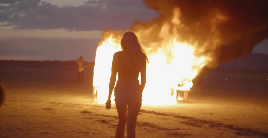 A woman walks towards a bonfire on the field