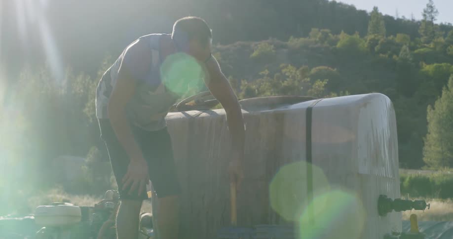 A man is stirring the contents of a bucket outside during the day