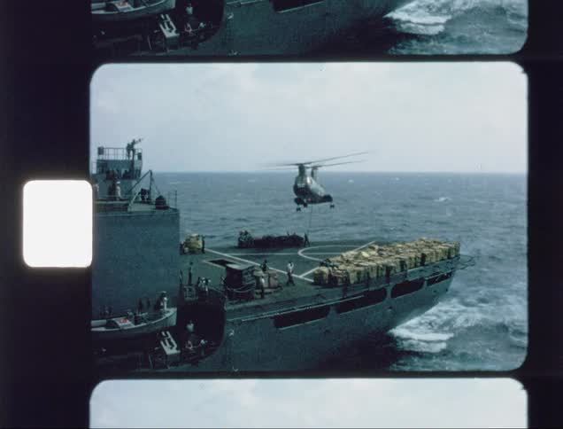 The helicopter lifts some cargo off the aircraft carrier