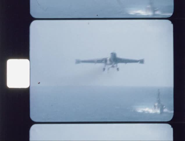 A jet flies towards an aircraft carrier