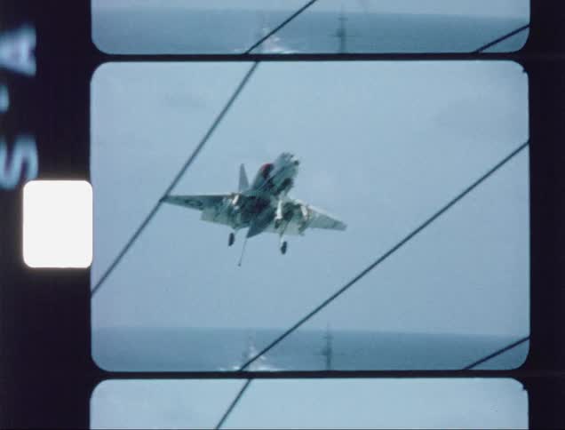 A fighter jet is preparing to land on an aircraft carrier during the day