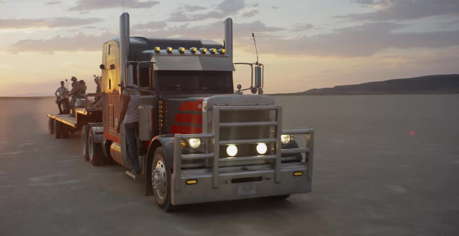 A large truck is driving with people partying on the bed behind