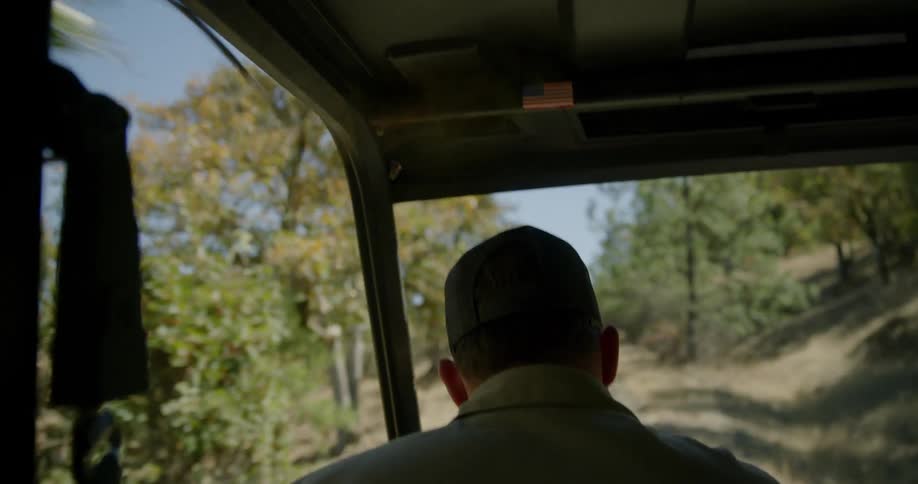 A man is driving an all terrain vehicle through some trees
