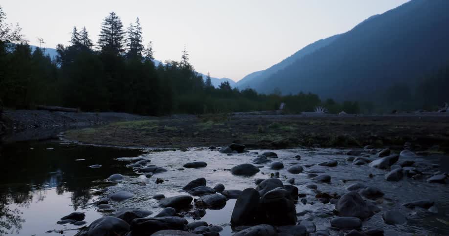 A river flows through a mountain forest at sunrise