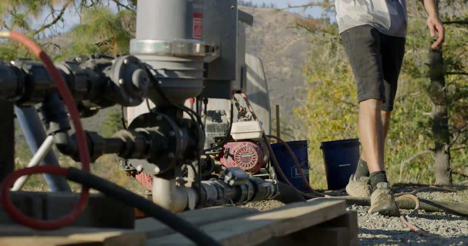 A man is walking past a water pump in daylight