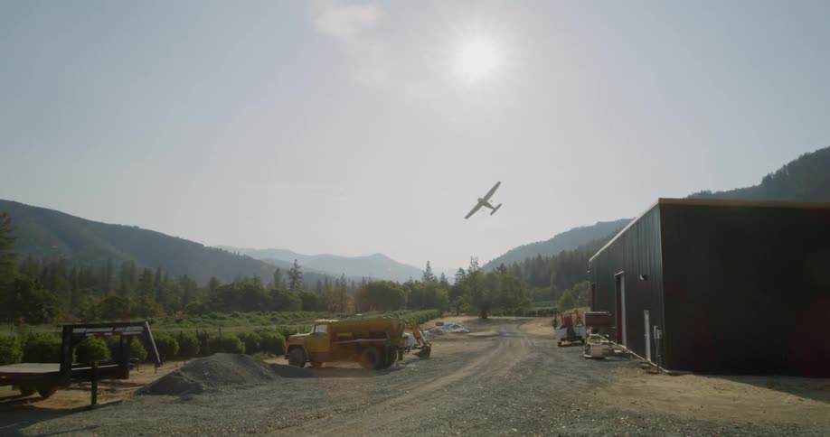 A small plane flies over a small farming operation