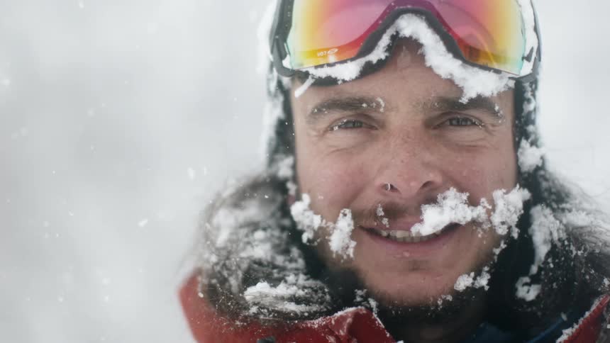 A skier smiles with snow on his face
