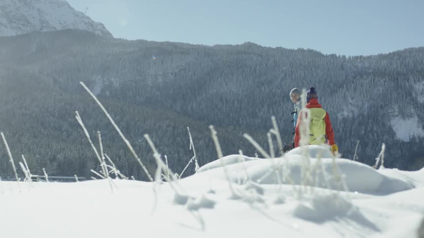 Two people walk over a snow filled mountain together