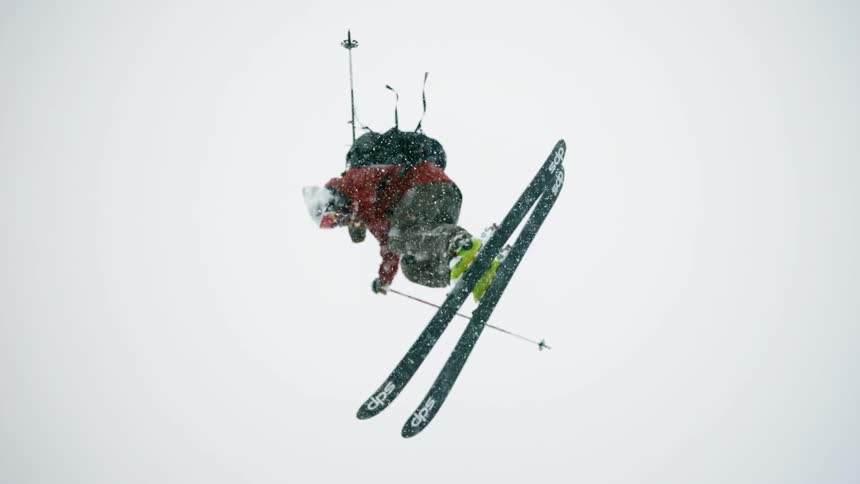 A skier spins through the air and lands in deep snow
