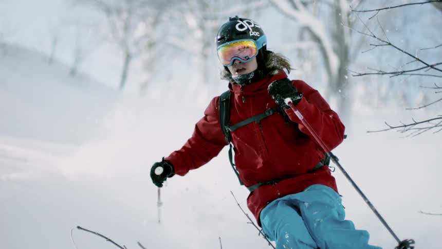 Person skis down a hill between trees