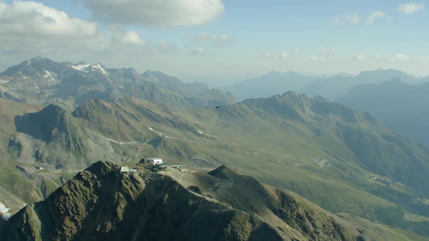The helicopter flies high over the green mountains