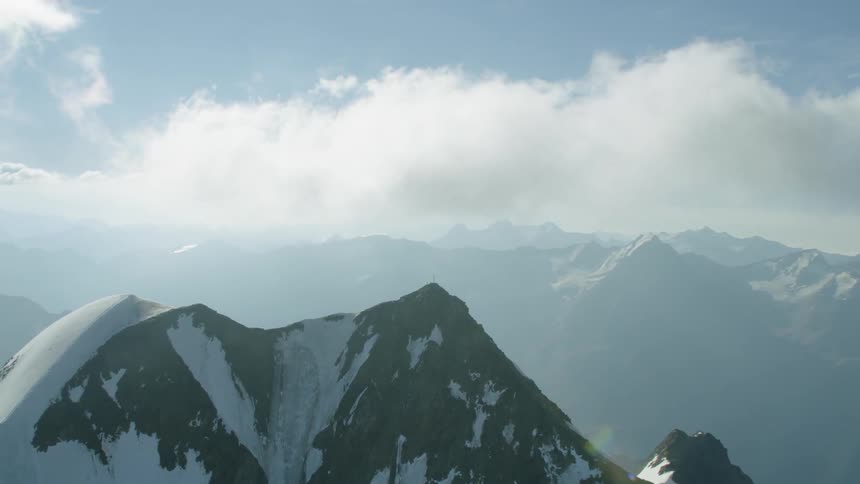 Clouds are hovering above mountain peaks during the day