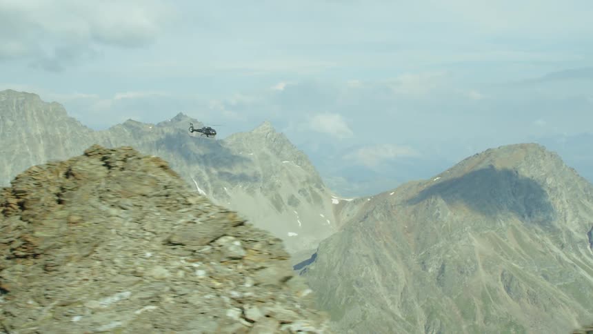 A helicopter flies over mountains
