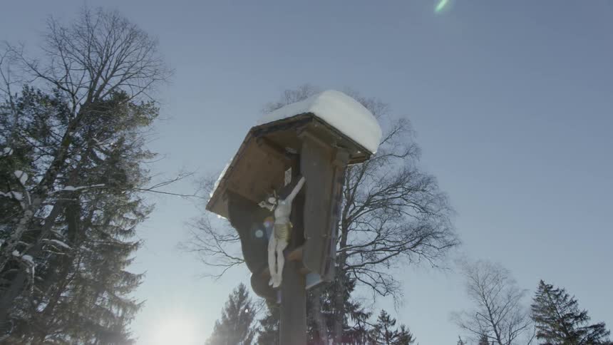 A statue of jesus on a crucifix is covered with snow