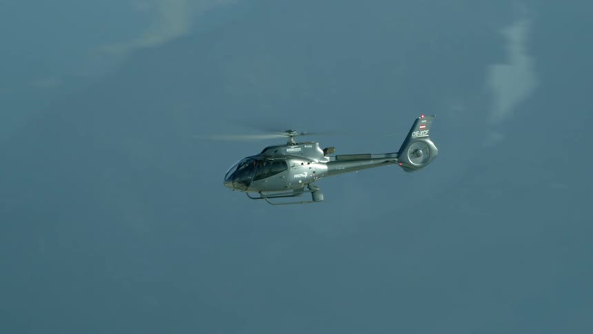 A helicopter flying over snow covered mountains