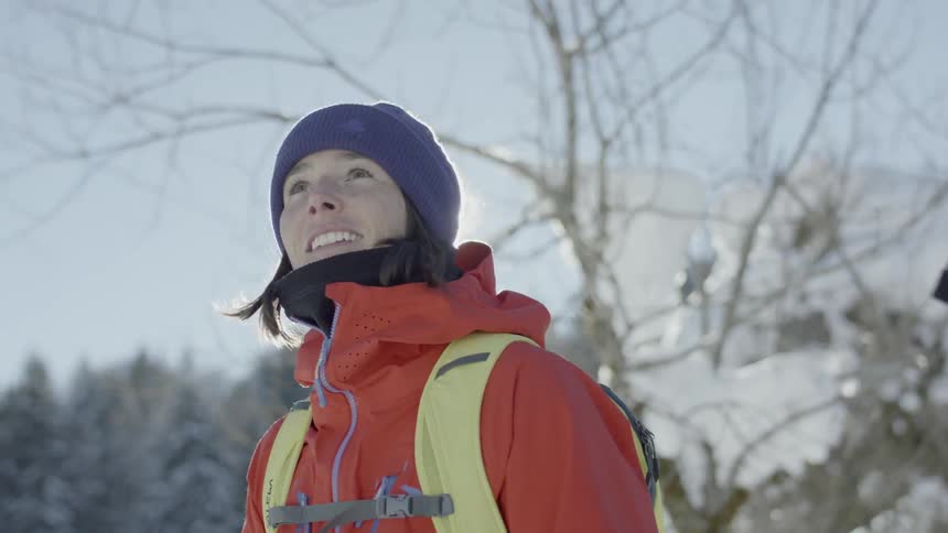 A woman wearing a backpack looks up and smiles