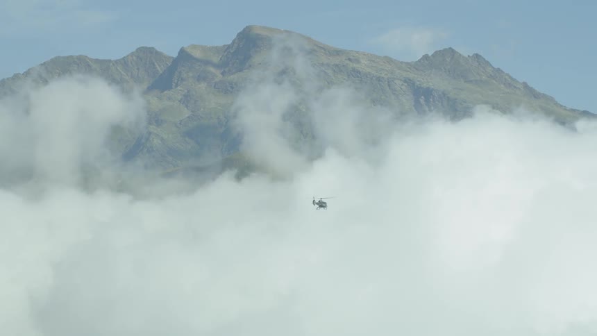 A helicopter flying through a very cloudy area in front of some mountains