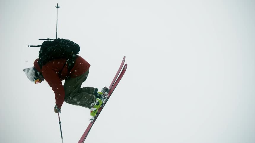 A skier spins through the air in a snowstorm