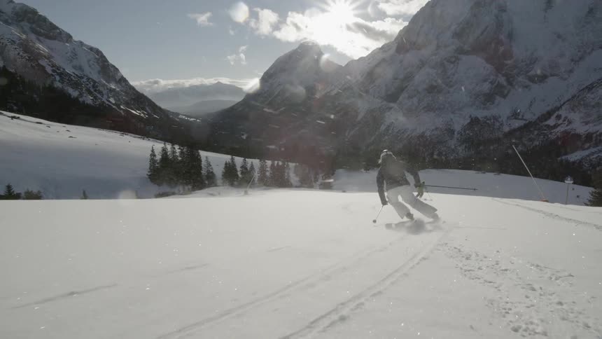 Skiers are skiing down a slope on a sunny day