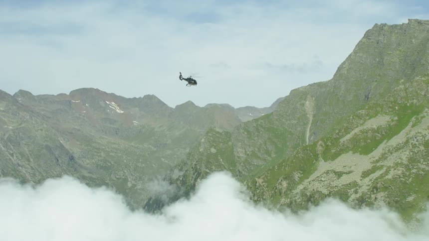 The black chopper moves towards the green mountains