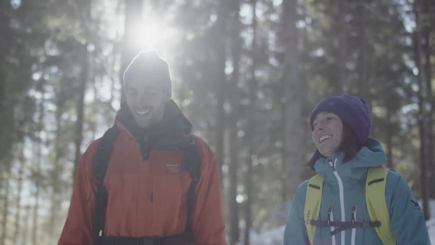 A couple are talking as they walk in a wooded area on a winter day