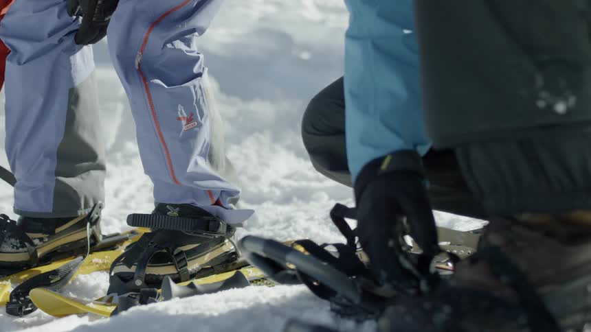 Two people put on snowshoes