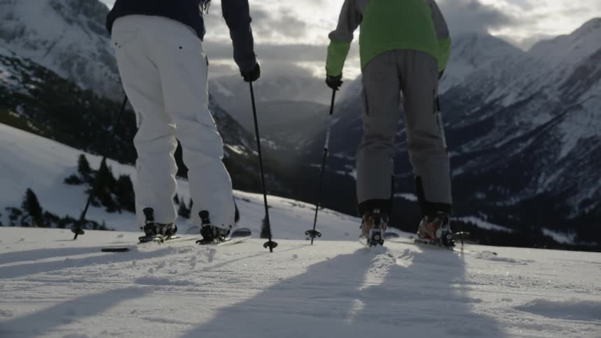 People in skis turn and face the slope and ski down