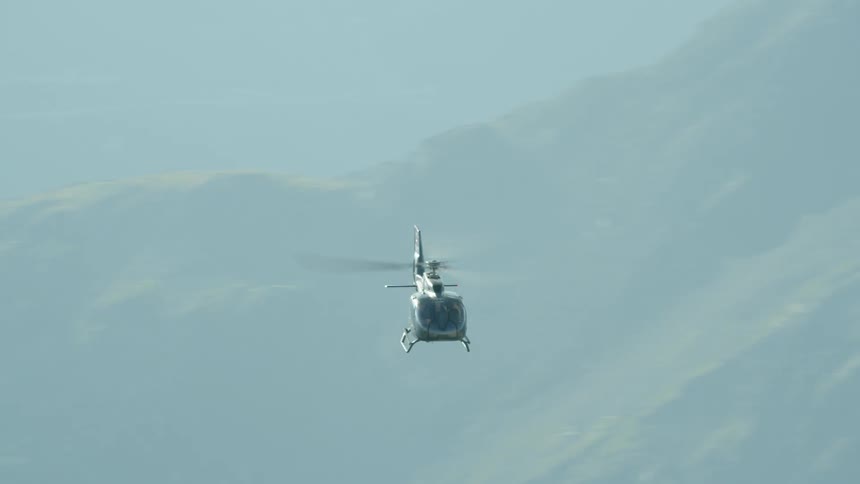 Helicopter flies low over rocky mountains