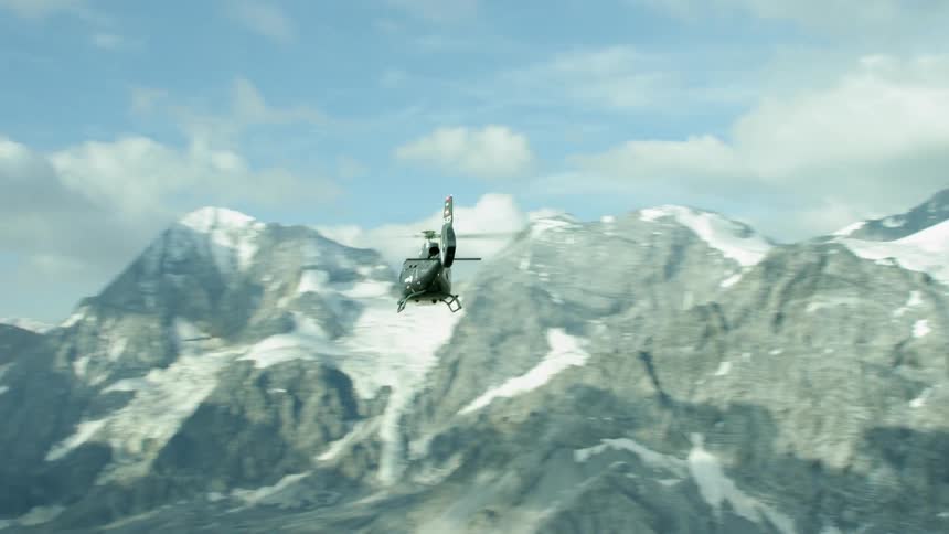 The helicopter moves downward on top of the mountain