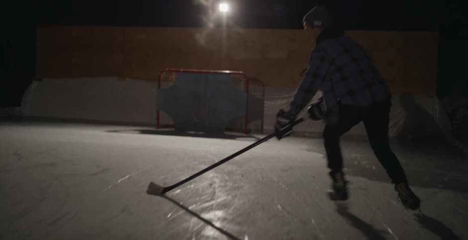 A hockey player skates on an outdoor ice rink