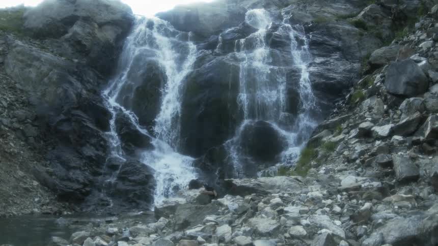 Waterfall cascading into a rocky basin and flowing down a small stream