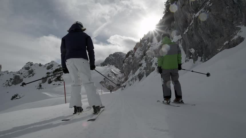 People ski down a slope on a mountain on a sunny day