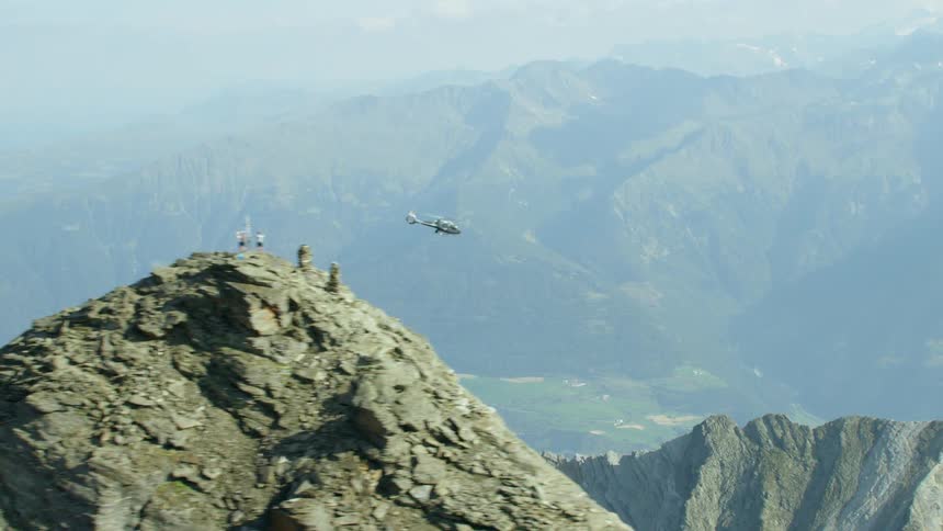 A helicopter is flying past people on a mountainside during the day