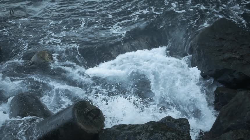 The water splashes around on the rocks of the shore