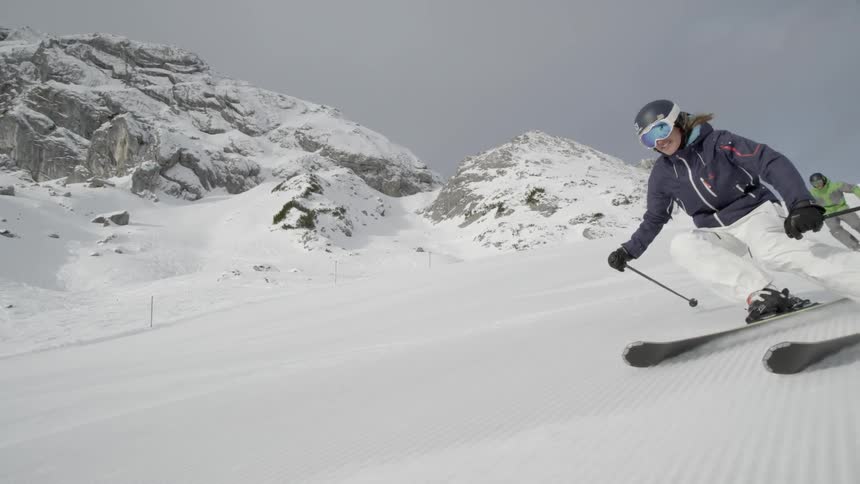 Two skiers swish down a slope on a sunny day