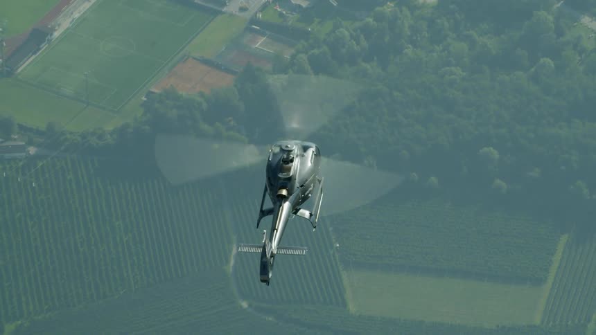 A helicopter hovers over farm fields