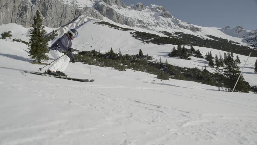 A skier is skiing down a mountain slope during the day