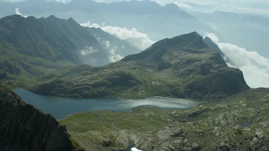 Clouds pass through and above tall moss covered mountains