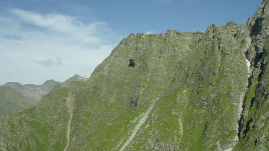 A helicopter flies over mountains