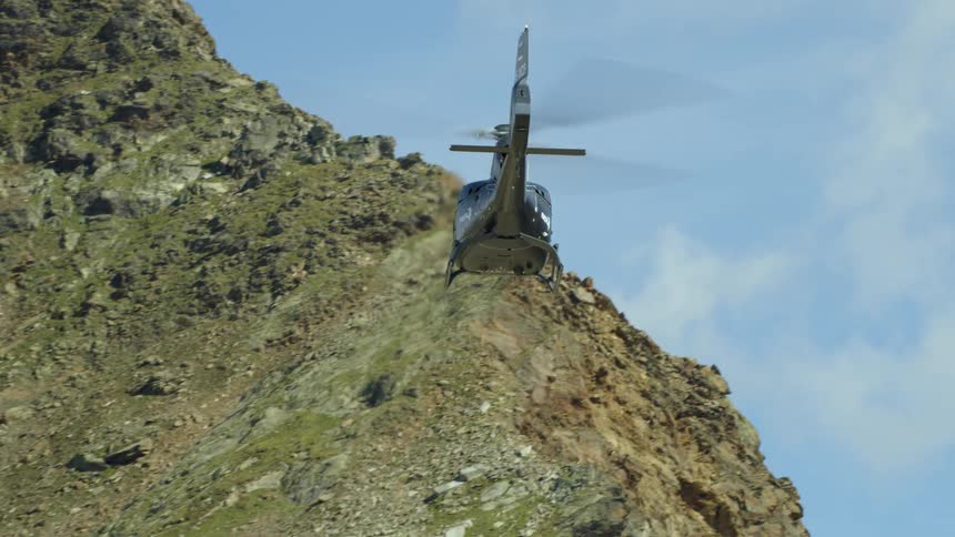 Helicopter flies low over rocky mountains