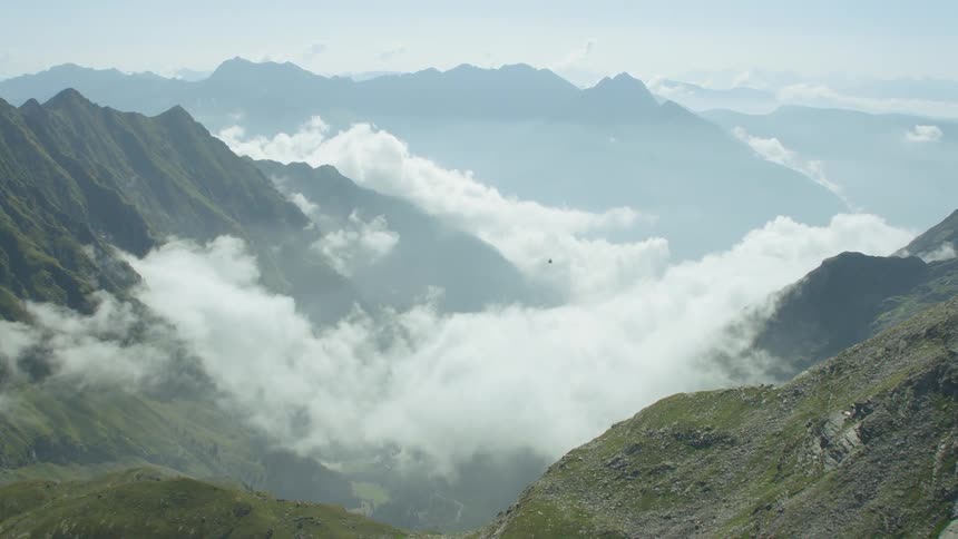 A helicopter is flying above a mountain range in daylight